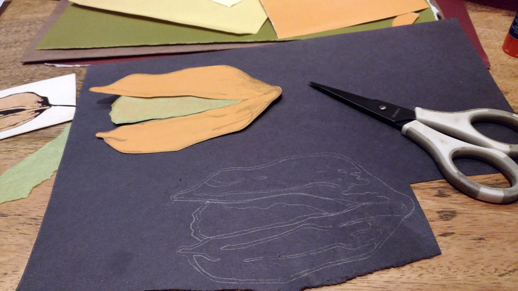 Orange and dark paper shapes for the logo, cut out next to a pair of scissors