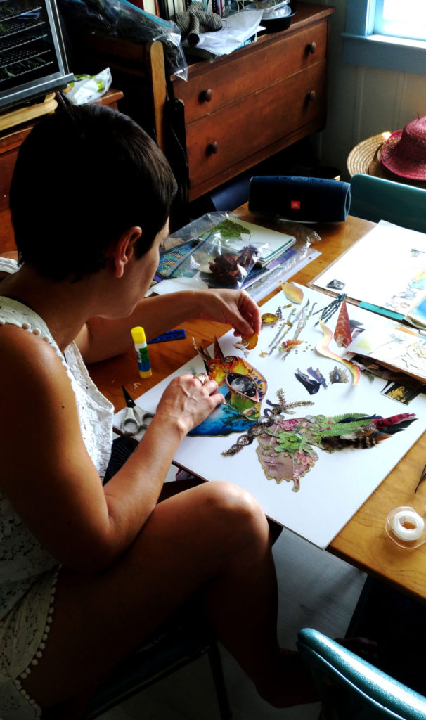 Yisca at her work table, gluing cut paper onto a collage