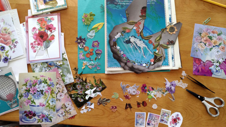 Postcards, flowers and cut pieces spread on the work table